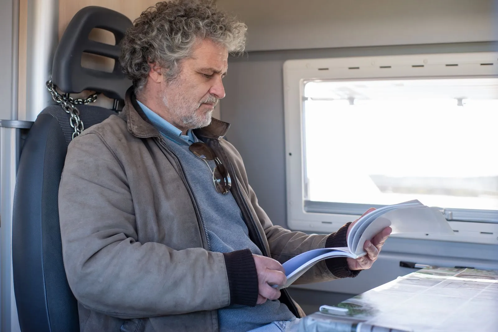 An adult man reading a book while sitting on a train in Portugal, providing a relaxed travel moment.